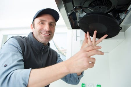 Un réparateur souriant remplace le filtre d'une hotte aspirante